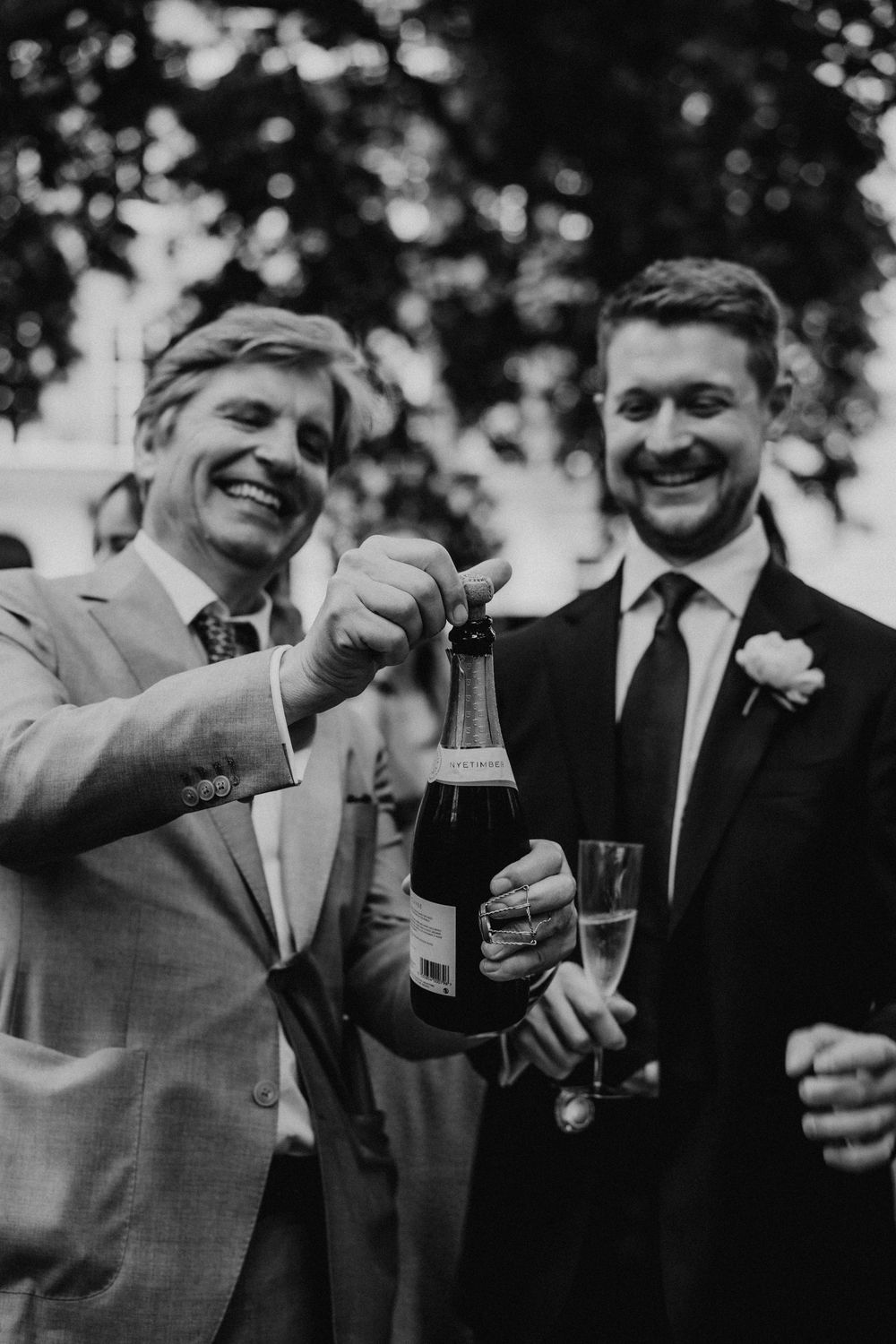 A group of men in suits sharing drinks and toasting together at an outdoor gathering.