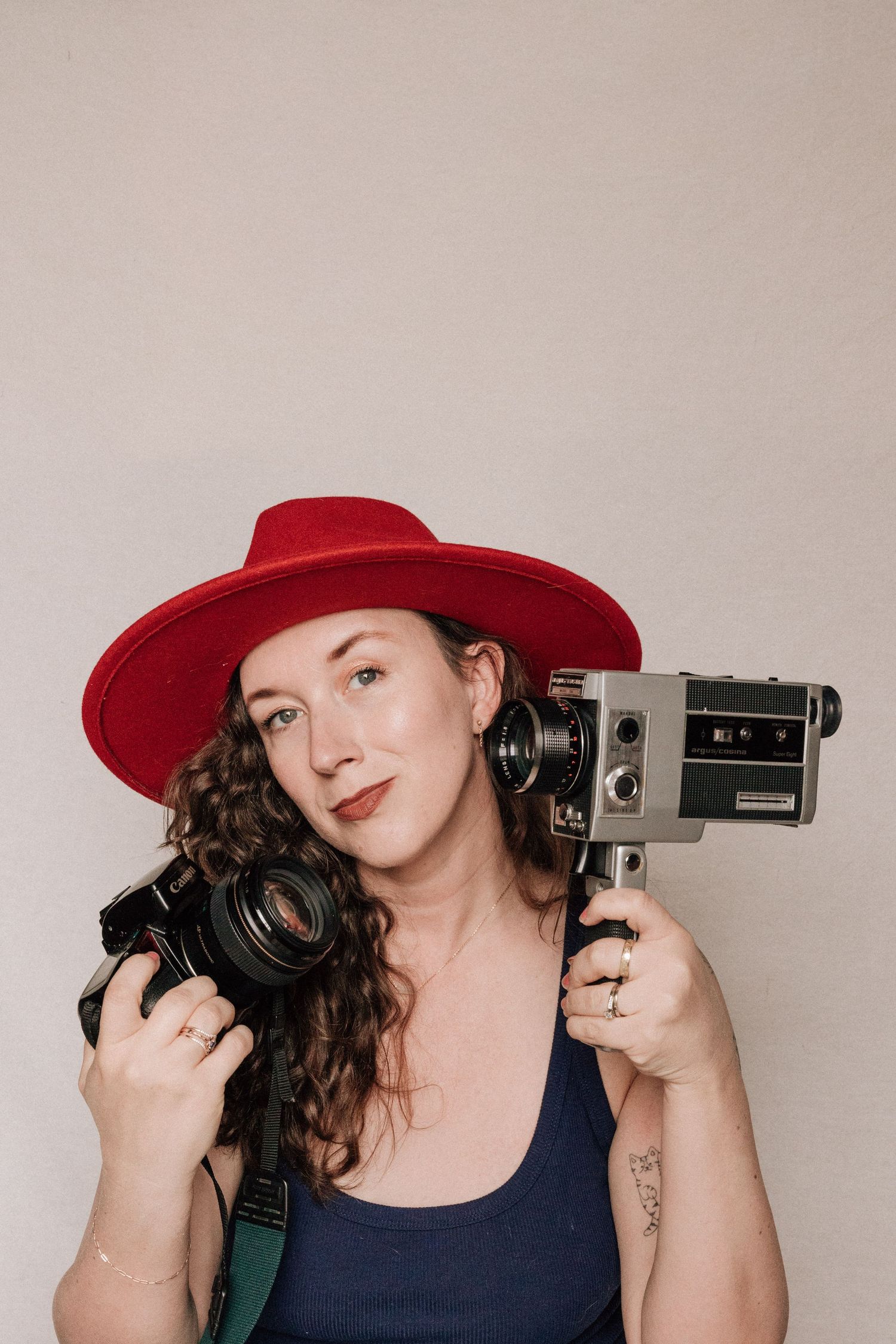 A woman holds a film camera and a Super 8 camera.