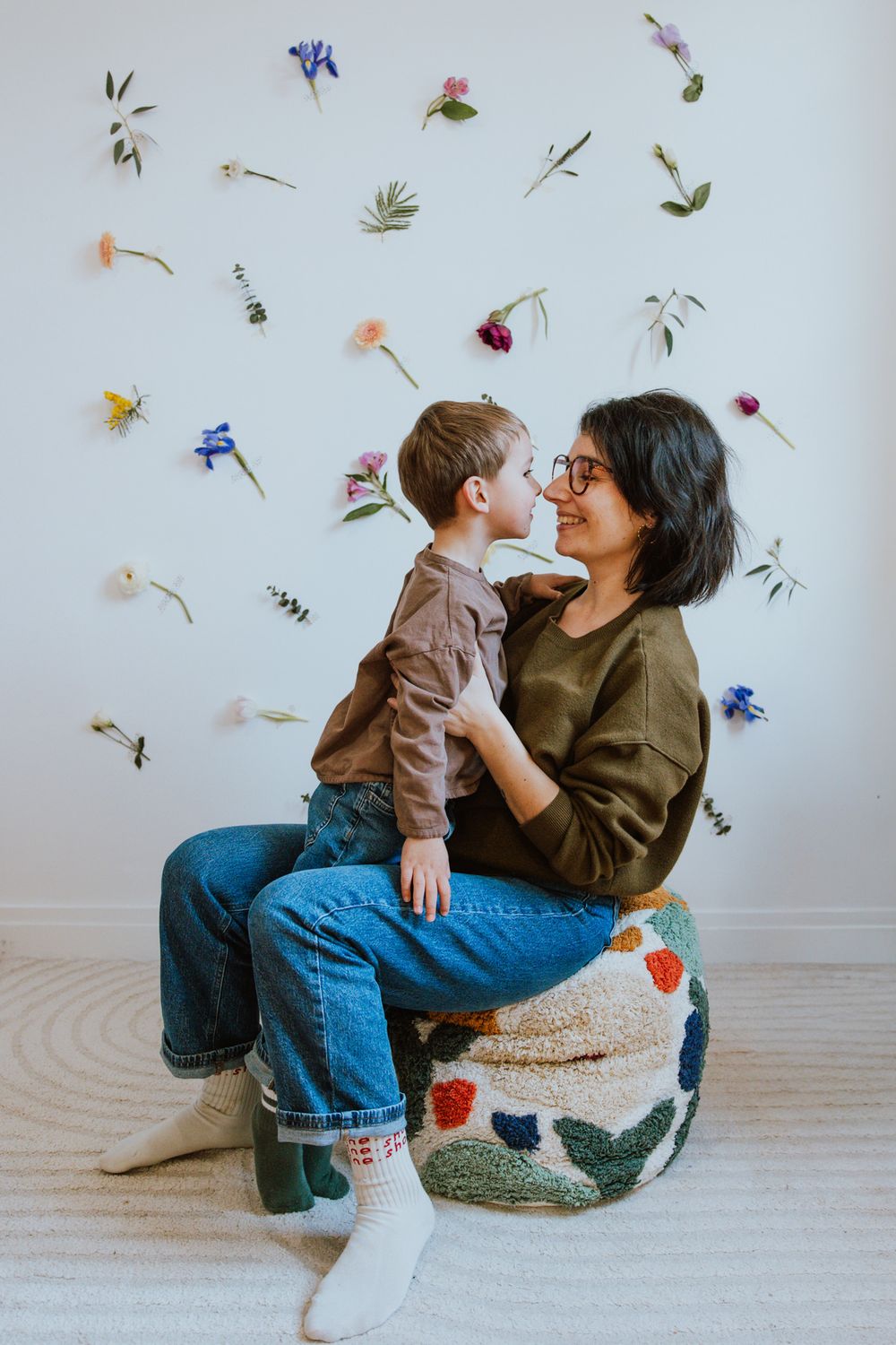 A playful scene with scattered wildflowers and petals against a white backdrop as two people share laughter.