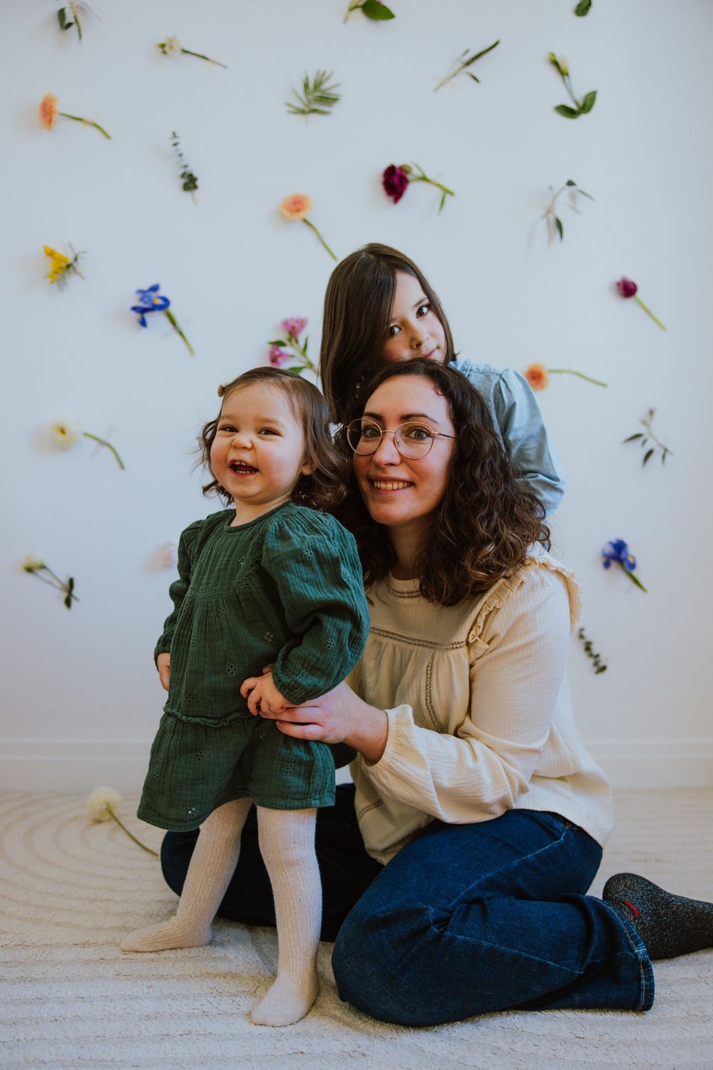 A series of playful candid moments against a white wall decorated with scattered flower petals and leaves.