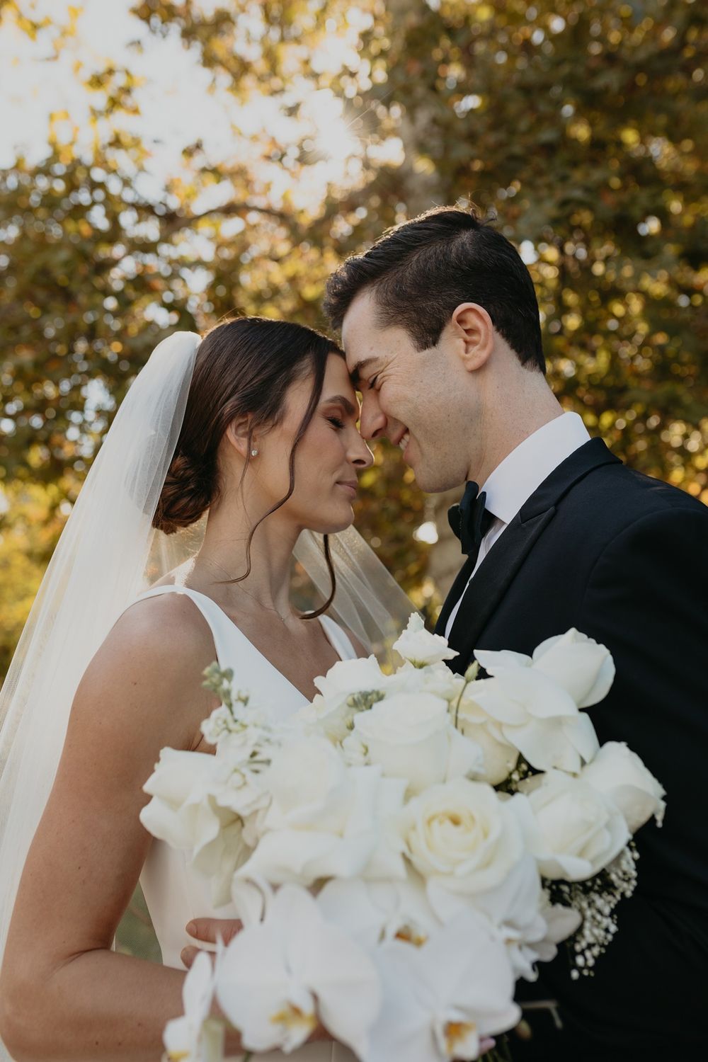 Romantic wedding sequence shows tender moments between newlyweds with white floral bouquet against autumn trees at Lake Oak Meadows.