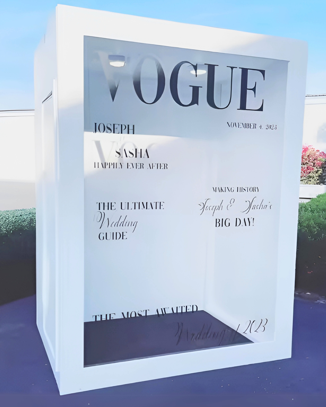 Custom white wedding welcome signs with elegant typography and Vogue-inspired design displayed at an outdoor venue.