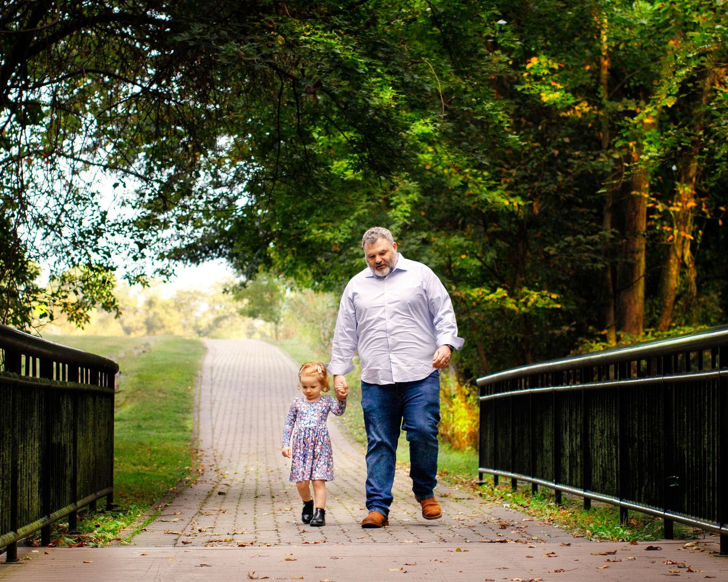Best Bergen County Family Photographer captures father and daughter walking hand in hand on bridge near Park Ridge, NJ