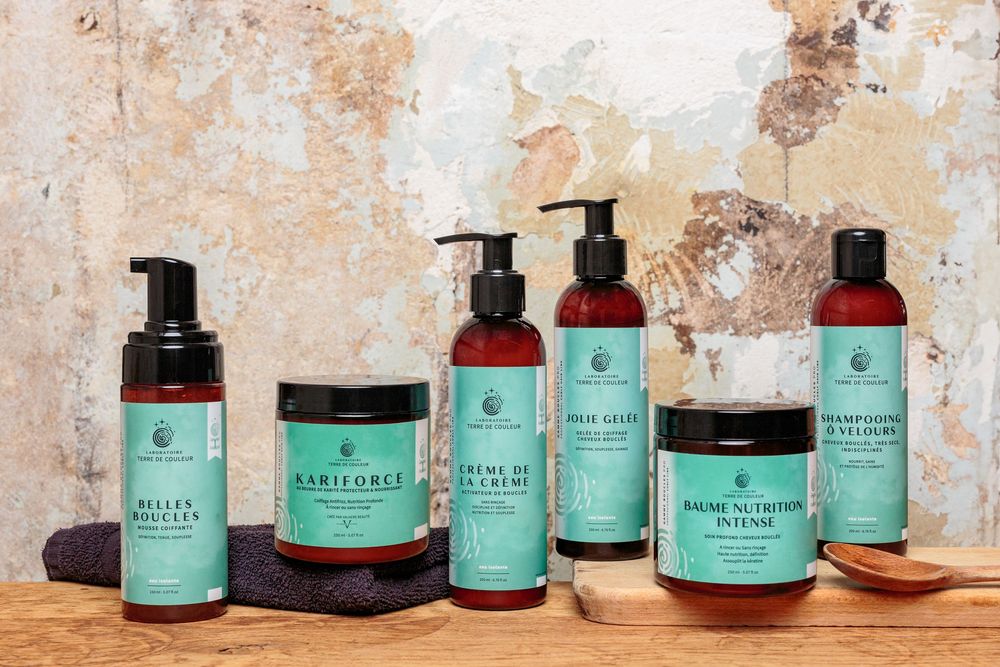 Complete Belles Boucles natural curly hair care product range displayed on wooden table.