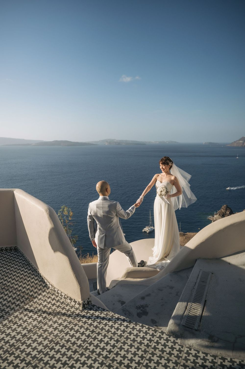 Scenic wedding moment on whitewashed steps overlooking the vast Aegean Sea in Santorini.