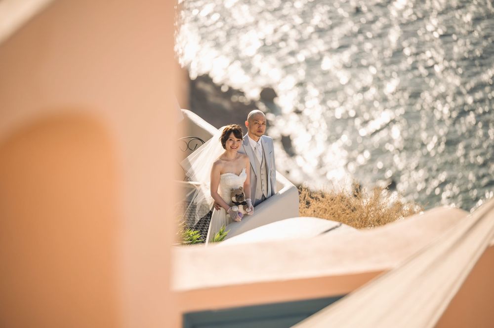 A romantic moment captured on a sunlit terrace overlooking sparkling Mediterranean waters.