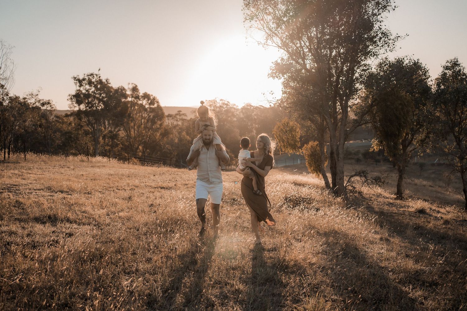 Dreamy hillside scene with person in white dress standing above foggy valley at sunset.