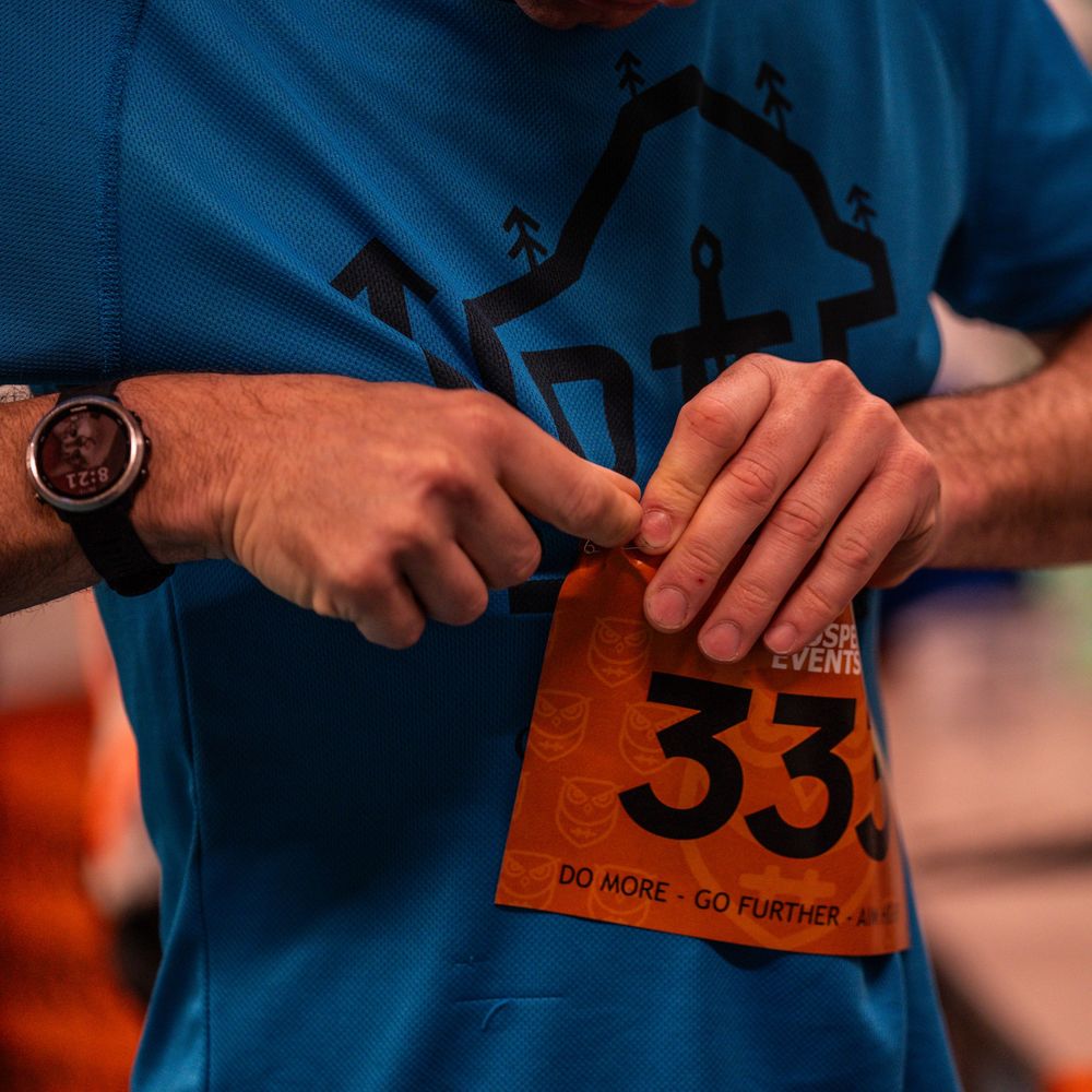 Close-up of runner attaching race number 33 to clothing during event preparation.