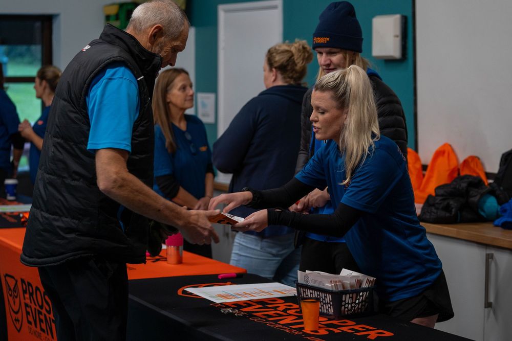 Registration desk at running event with volunteers distributing race materials.