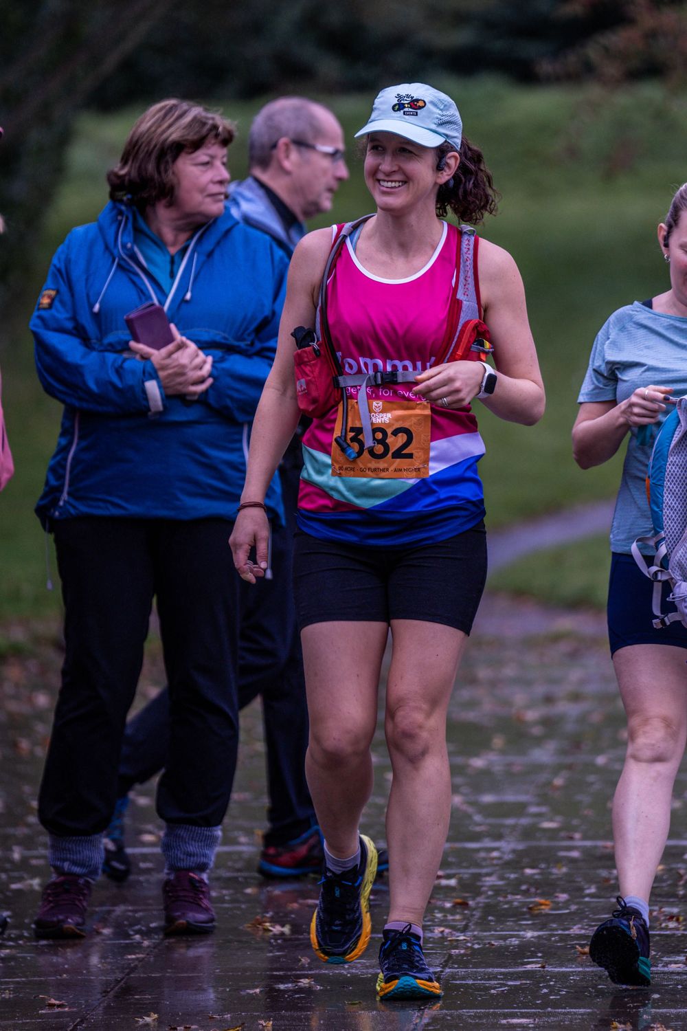 Runners participating in rainy day race wearing athletic gear and numbered bibs.