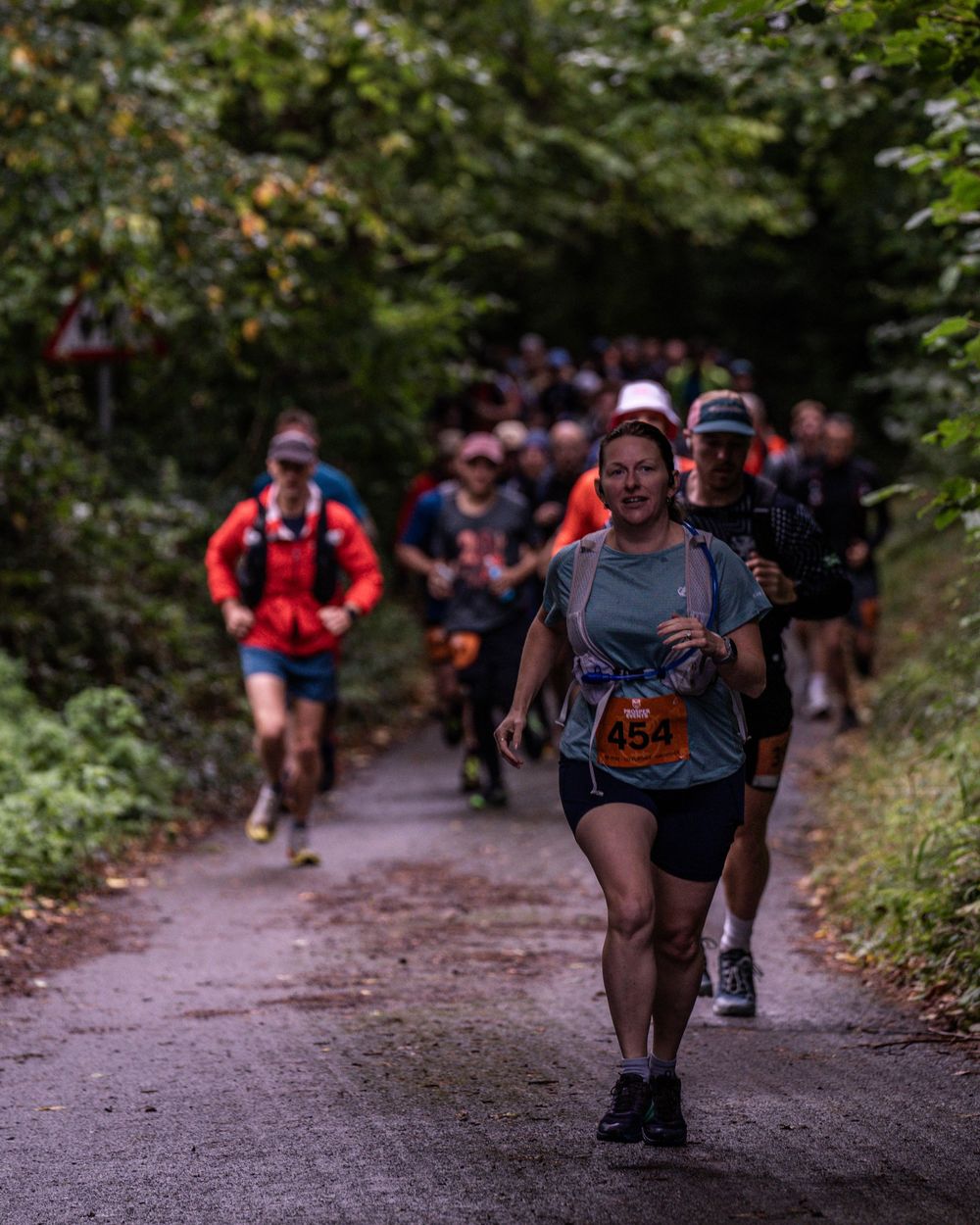 Trail runners competing on a forested path during an autumn race.