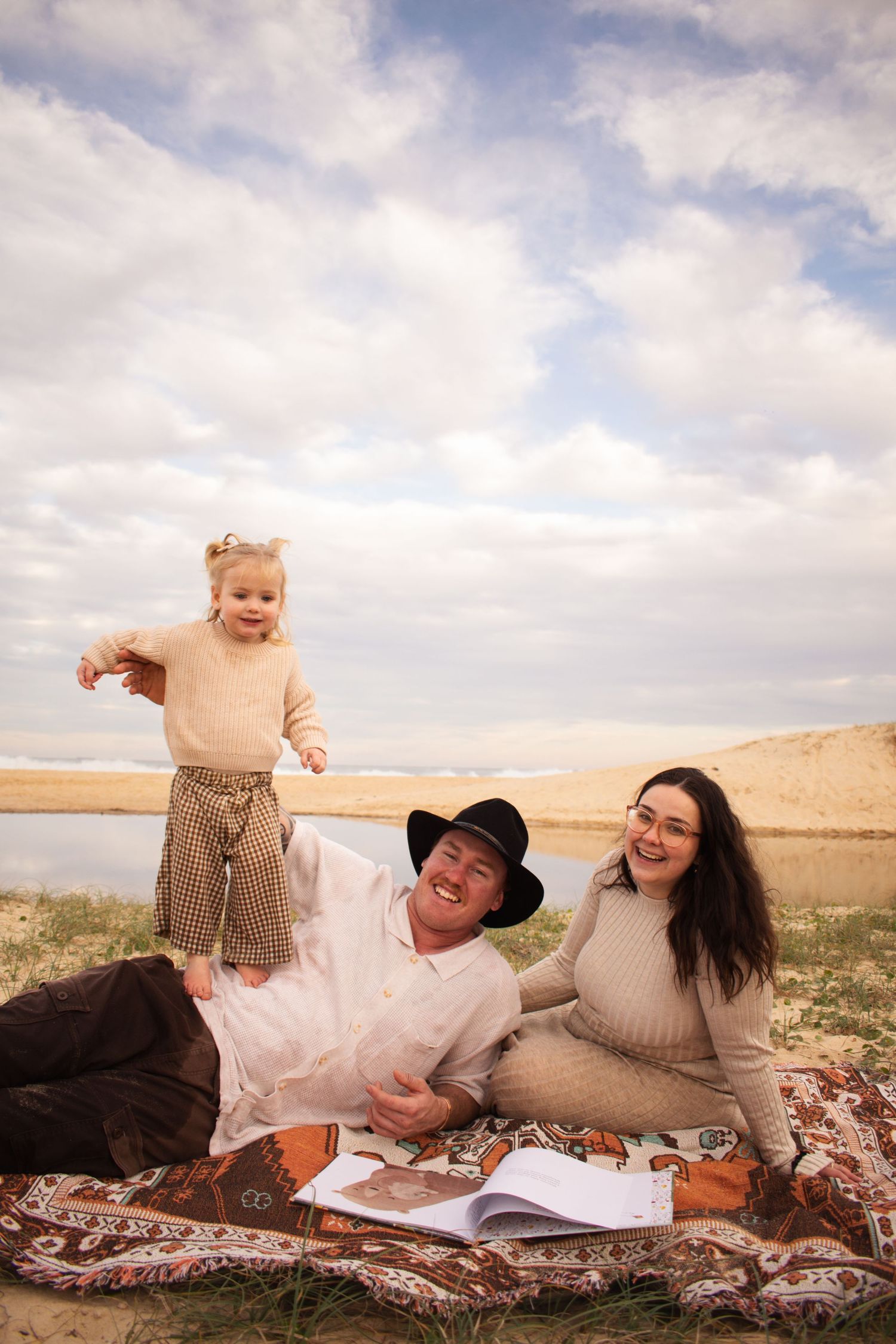 Newcastle maternity photographer capturing mother-to-be at beach with husband and toddler