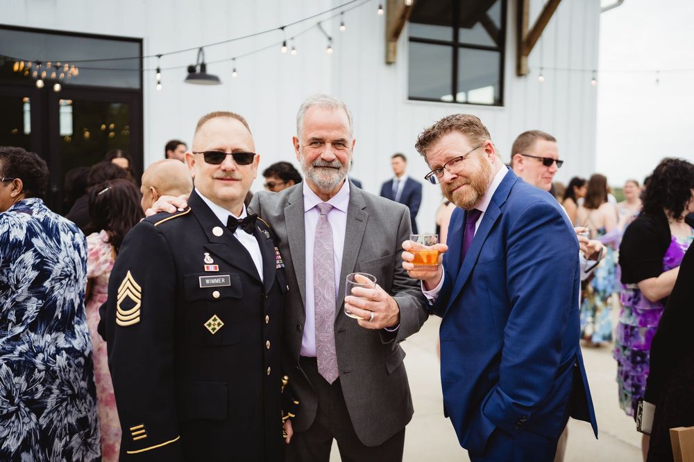 A group of well-dressed guests enjoying drinks and conversation during an outdoor social gathering at an event venue.