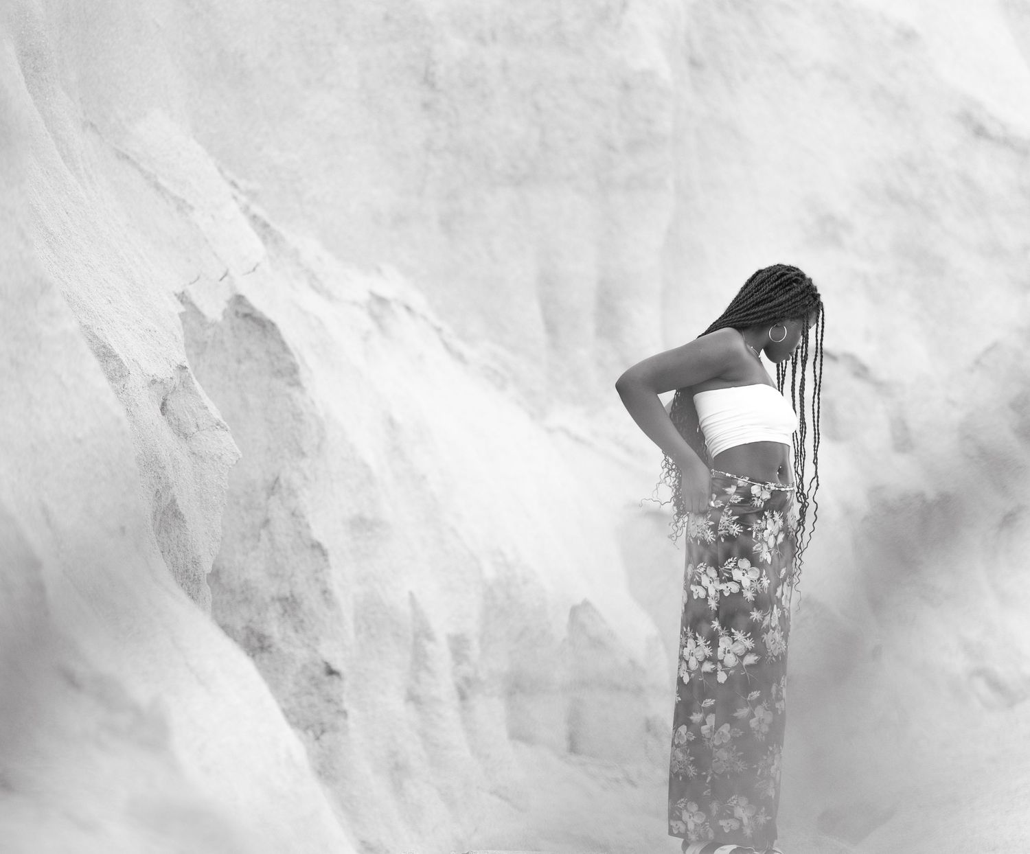 Black and white artistic photo of a person in floral dress standing against misty background.