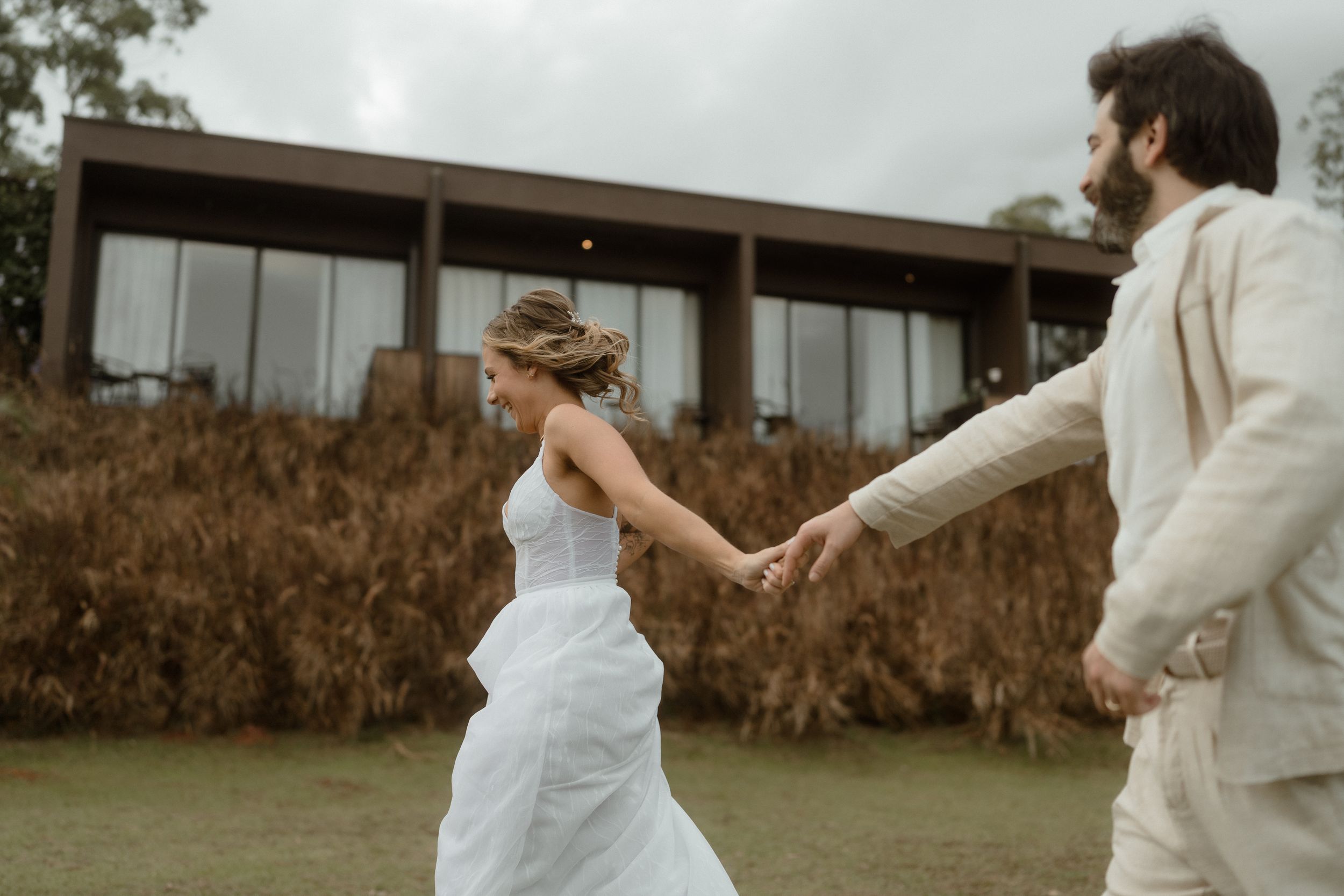 A couple shares a joyful moment on their wedding day outside a modern building.