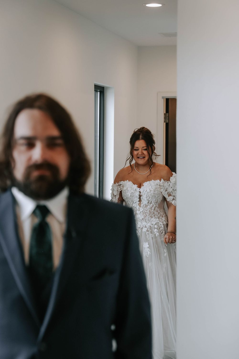 A touching first look moment between a couple during their wedding day in a bright hallway.