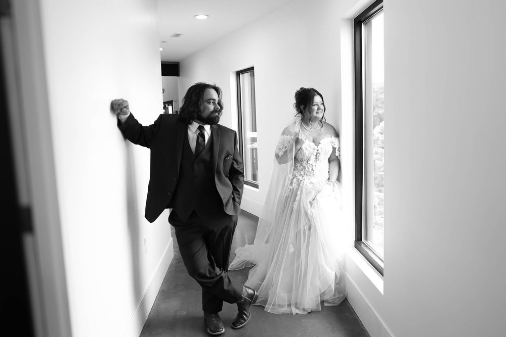 Candid black and white photo of newlyweds walking and celebrating in a hallway.