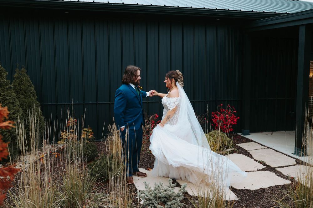 A couple having their first look moment outside a modern black building with autumn decorations.