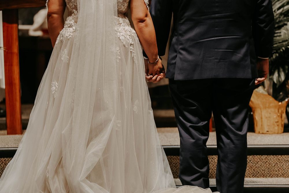 A close-up view of a bride and groom holding hands during their wedding ceremony.