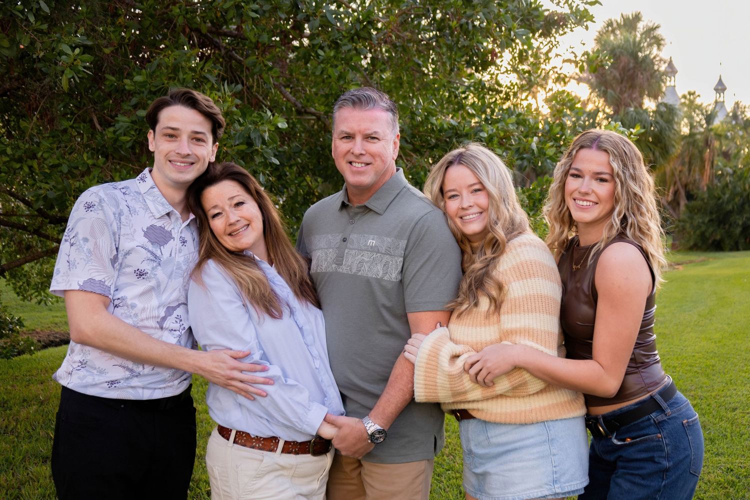 Group portrait of five people in casual attire standing together in a lush garden setting.