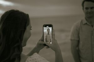 Candid lifestyle photo in Florida — smartphone captures partner in the background during a creative, sepia-toned beach session.