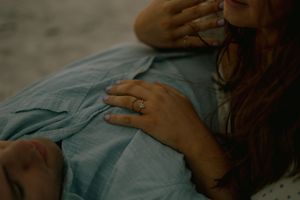 Close-up from a maternity session in Clearwater, FL — hands resting on a blue dress, showcasing a wedding ring in soft light.