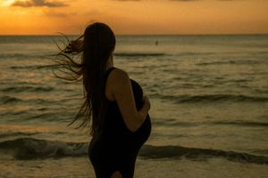 St. Petersburg, FL, beach photography — moody silhouette of a woman with long hair facing the waves during a lifestyle ocean session.