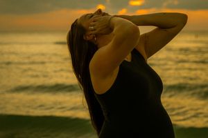 St. Petersburg, FL, golden hour beach portrait silhouette of a woman in a black top at sunset, lifestyle session by the ocean.