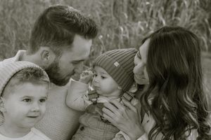 Black and white lifestyle family portrait in Hamilton — tender outdoor moment between parents and kids captured naturally.