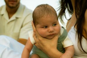 Hamilton newborn photography — baby smiling while being held by parents during a candid in-home family session.