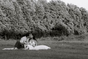 Black and white couples photography in Hamilton — intimate outdoor session in a grassy field with tree-lined backdrop.