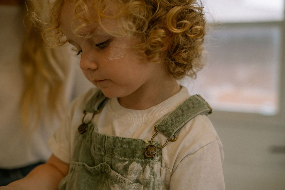 Candid child portrait at home — lifestyle family photography in Hamilton featuring a toddler in overalls and natural light.