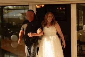 Candid wedding photography in Seminole, FL — bride and father walking through softly lit indoor venue during reception.