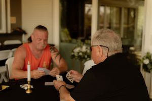 Two family members playing cards at a candlelit table before an intimate Florida reception.