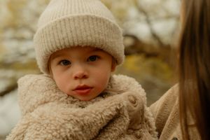 Candid outdoor family photo in Hamilton — child in cream winter gear during a cozy, cold-weather session.