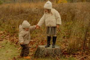 Golden hour family photography in Hamilton — children in cozy winter outfits exploring a field filled with fall leaves.