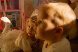 Candid sibling moment during an in-home lifestyle family session in Kitchener — soft golden light and natural curiosity.