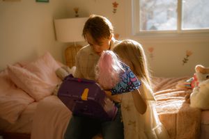 Father and daughter moment during a lifestyle family session in Hamilton — soft morning light, pink bedding, and childhood connection.