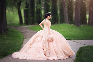 Romantic peach-colored ball gown photographed in a serene woodland setting.