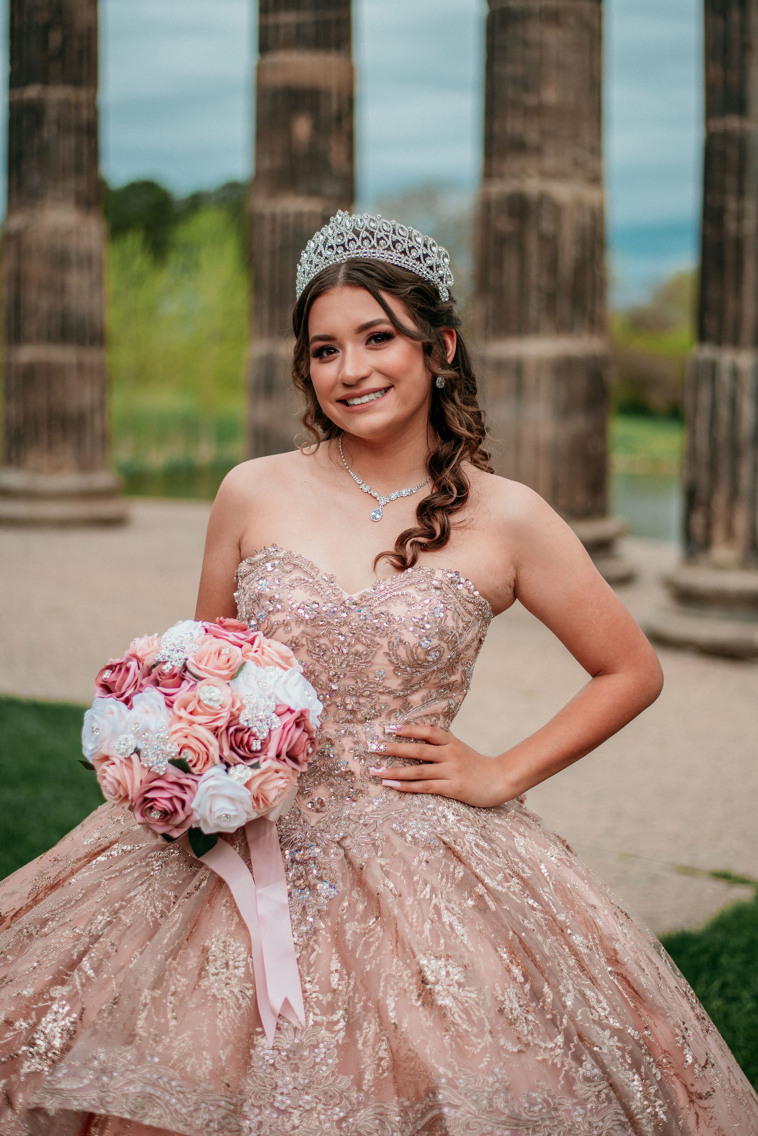 A sparkly rose gold quinceañera dress with intricate beading and floral bouquet details.