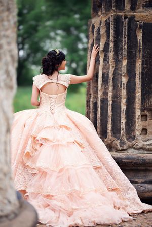 Delicate blush pink ball gown photographed against historic stone columns.