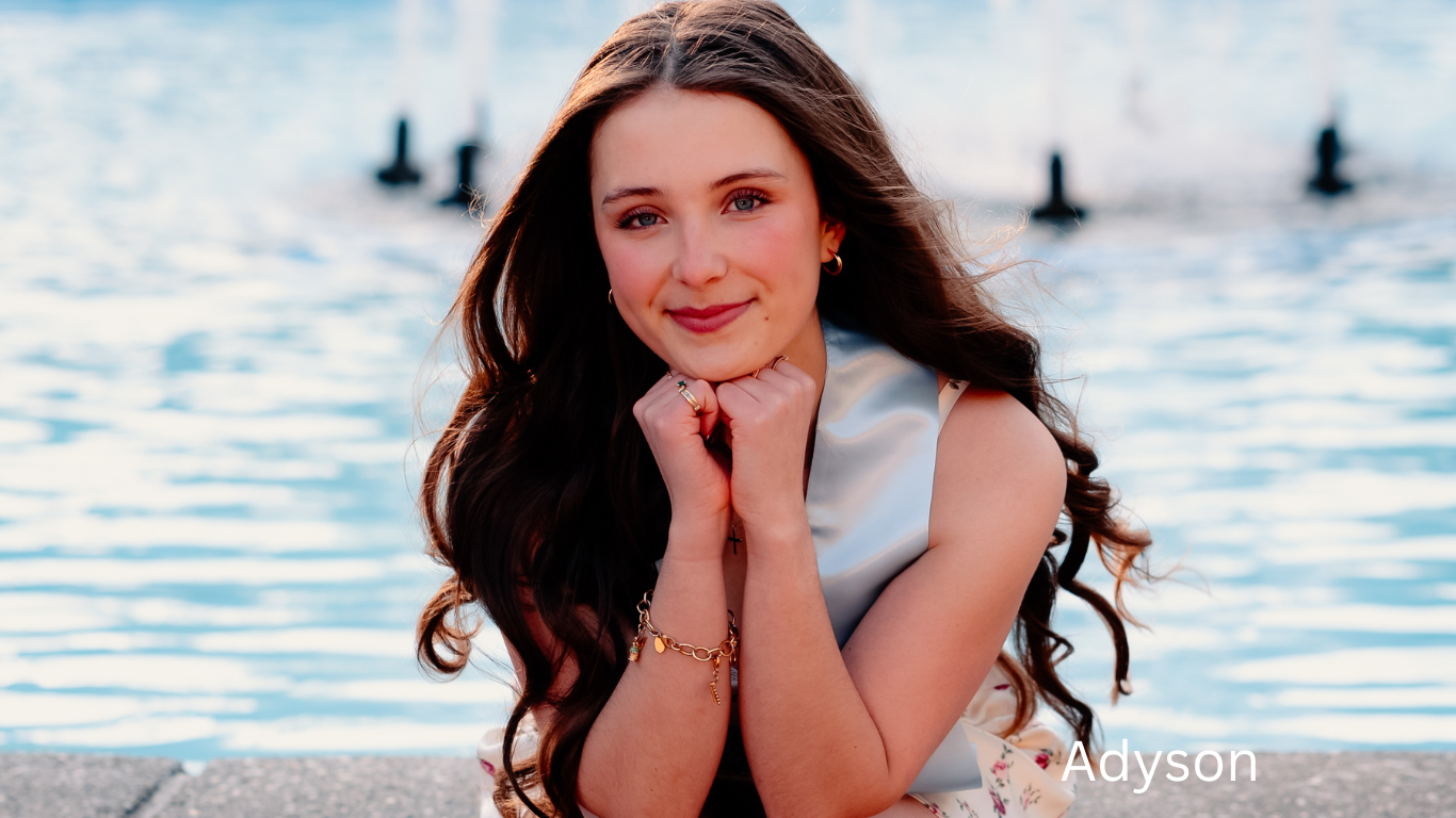 Portraits taken by a waterfront with soft natural lighting and reflective water in the background.