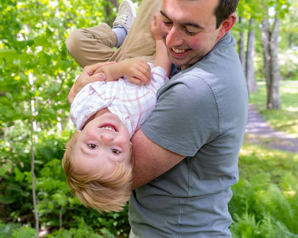 Playful moment between parent and child during outdoor family photoshoot during a family photo session in Sudbury, MA outside Boston.