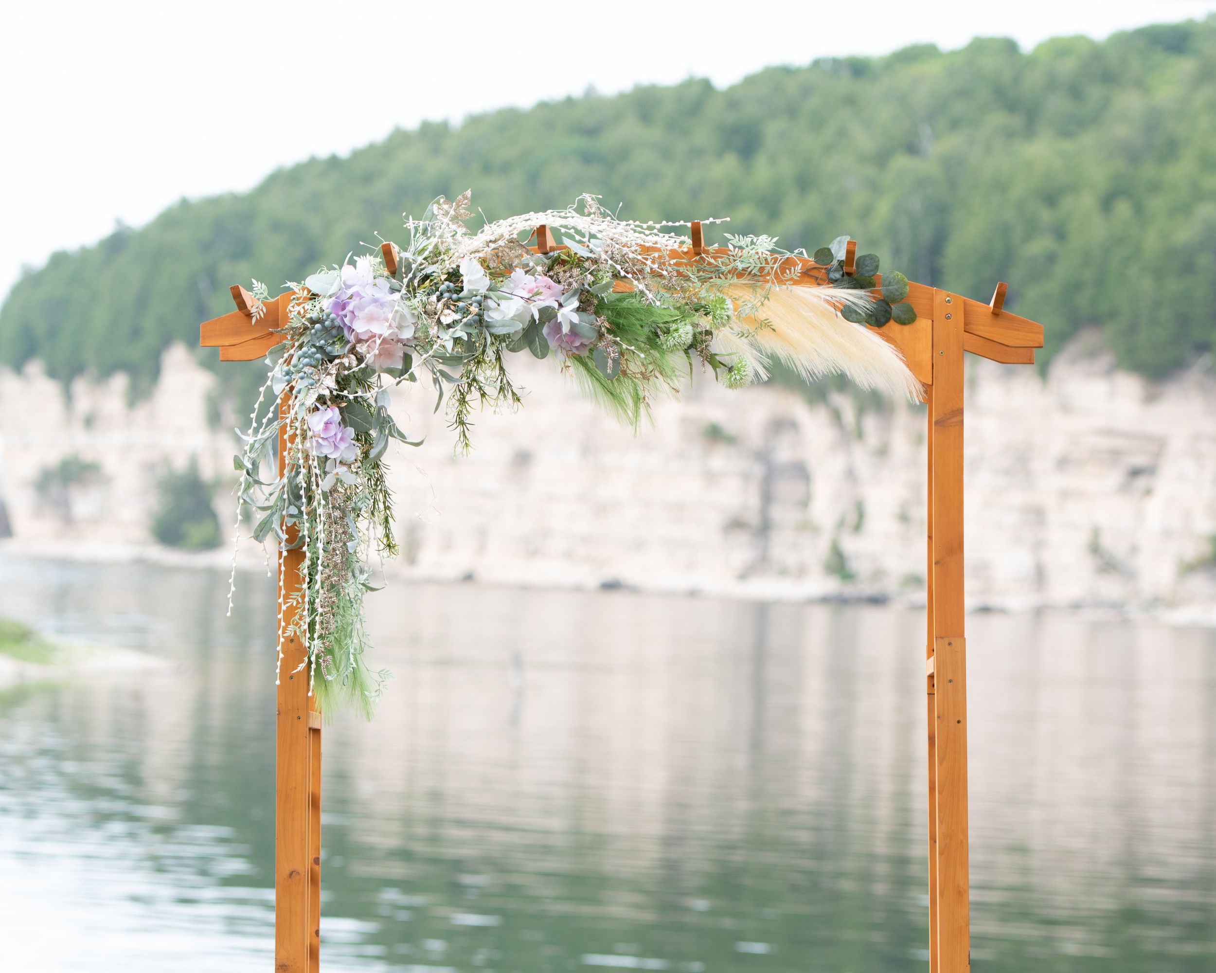 A wooden wedding arch decorated with greenery and white flowers overlooking lake michigan at fayette state park
