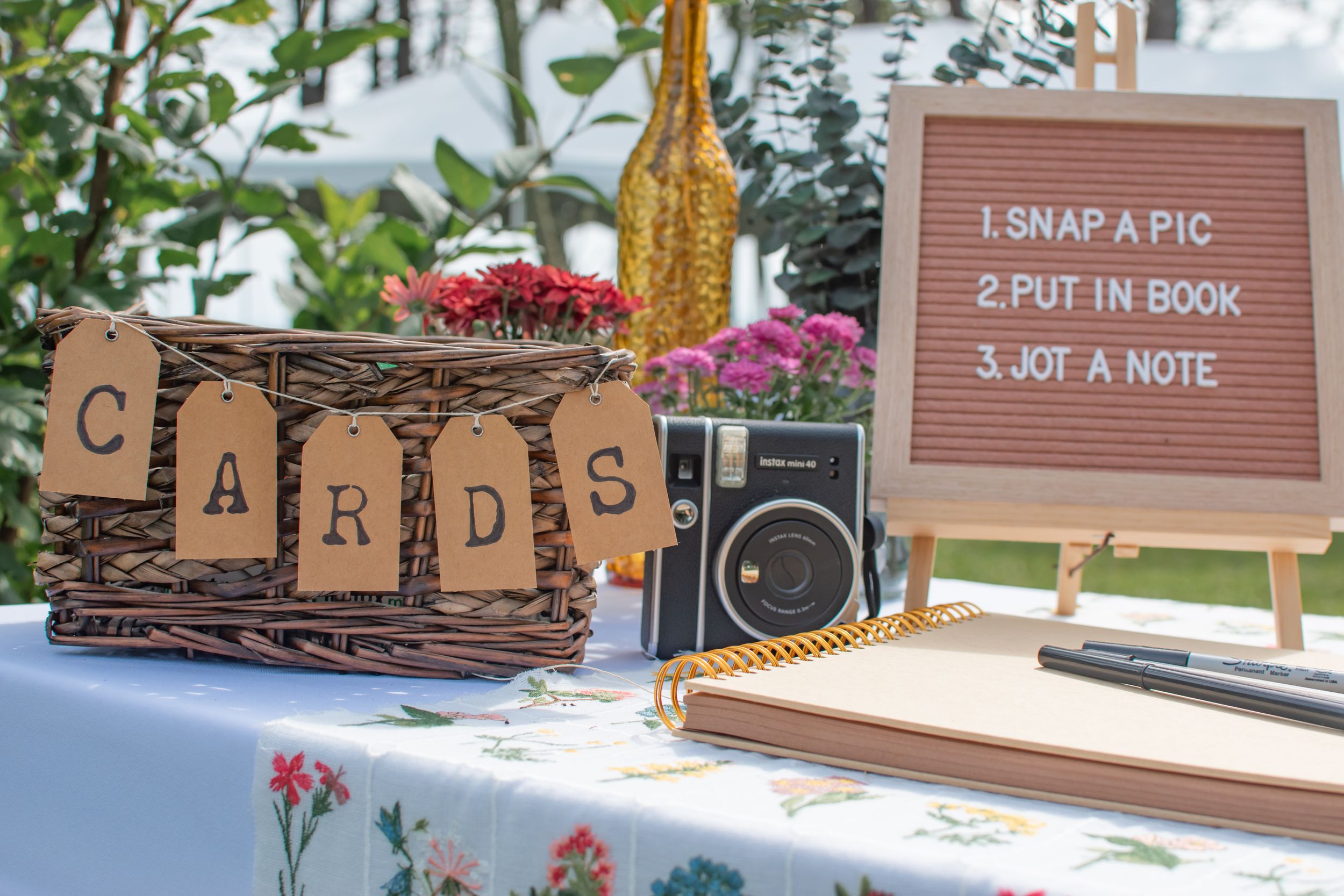 A rustic wedding guest book table with vintage camera and wooden cards sign.