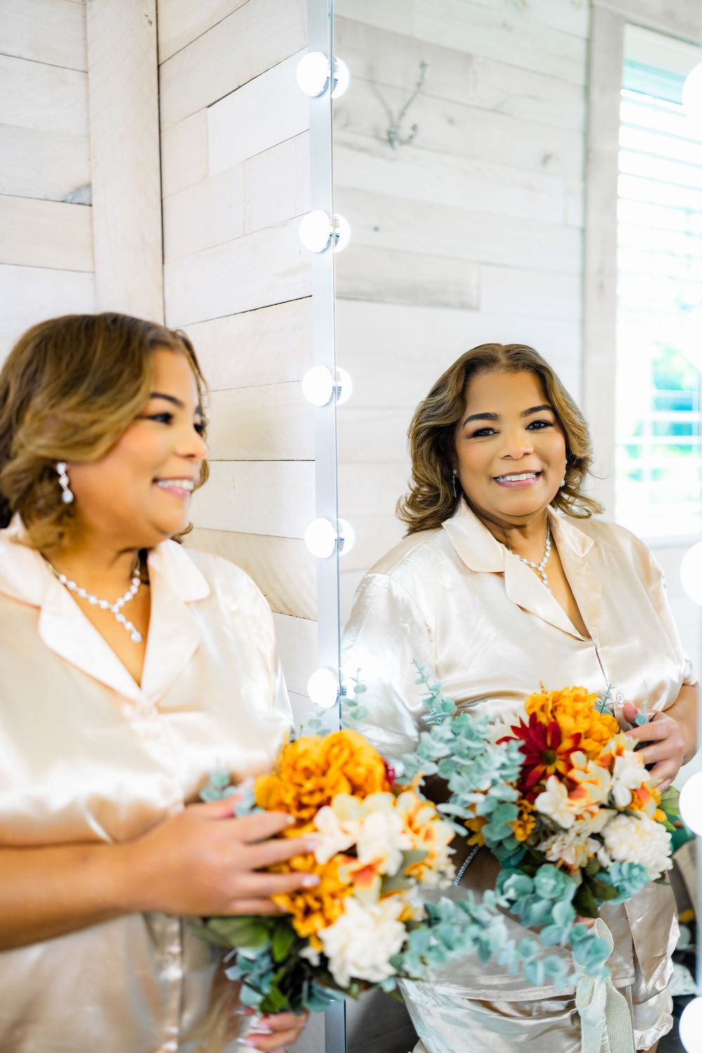 Reflection shot of someone holding a colorful autumn bouquet while wearing a white satin top.