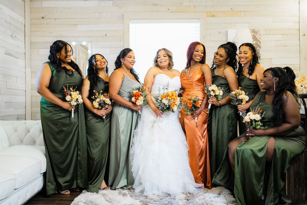 Wedding party poses in olive green and copper dresses while holding beautiful floral bouquets.