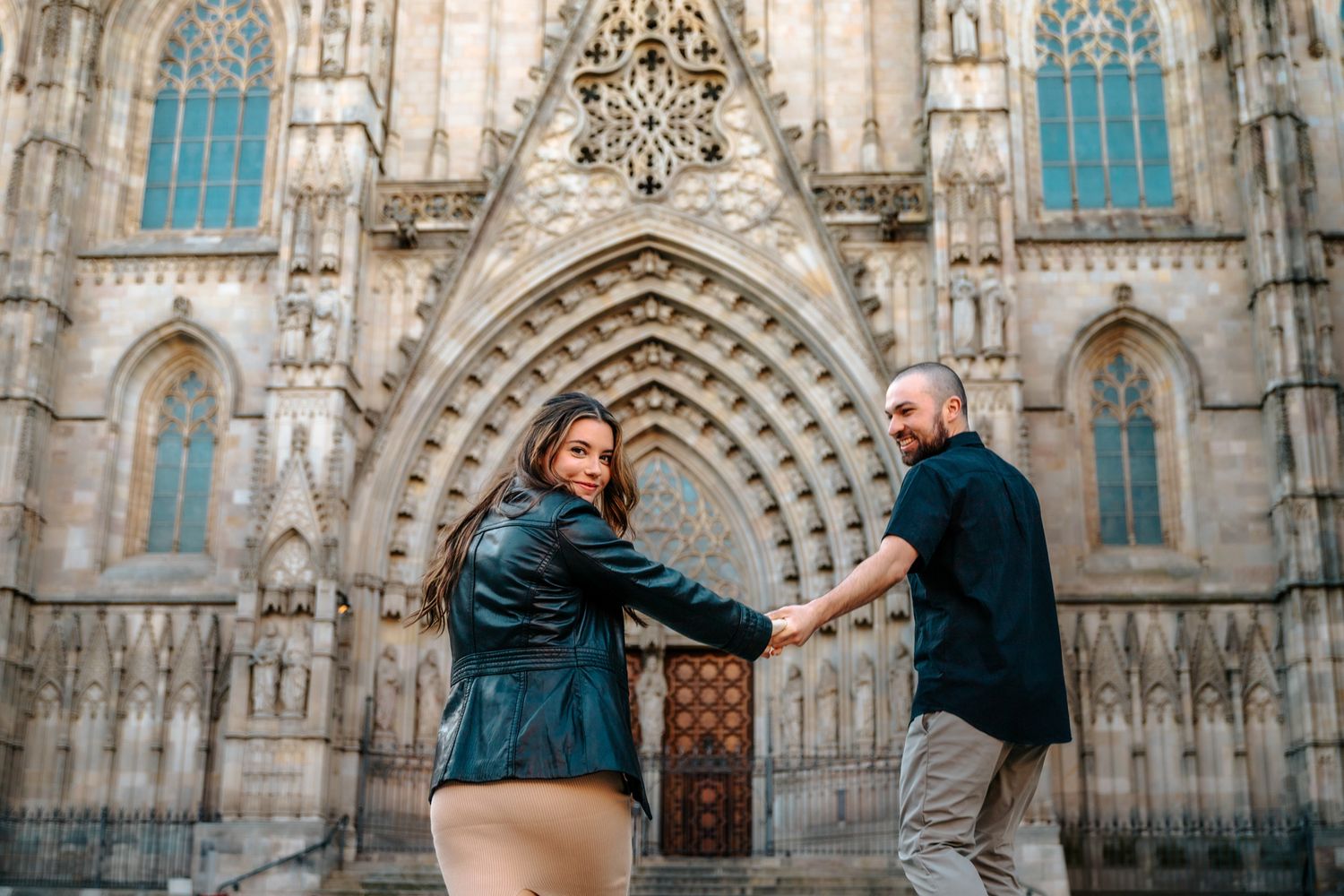Soft morning light falling on the couple as they laugh in a Gothic Quarter alley.