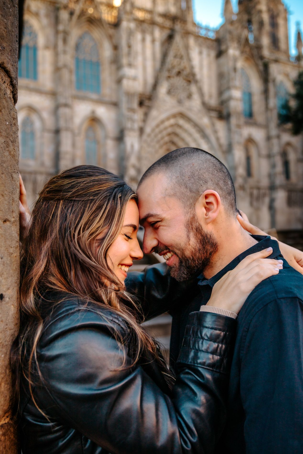 Angelina leaning on Jared’s shoulder beneath a stone arch in the Gothic Quarter.