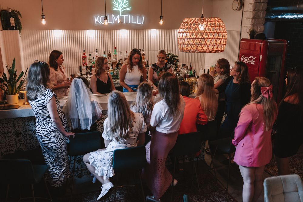 A lively group gathers at a bar or event space with modern lighting fixtures and decor during a social gathering.